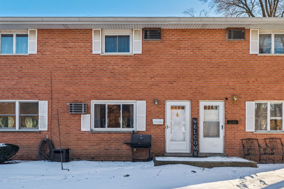 Front view of a brick two-story house with multiple windows and doors.
