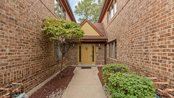 Front view of a brick house entrance with a yellow door.
