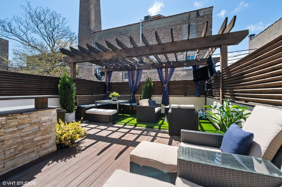 Rooftop patio with wooden pergola, outdoor seating, and decorative plants.