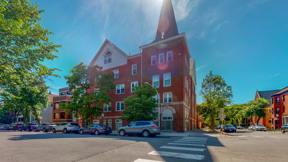 Front view of a multi-story brick building on a street corner.
