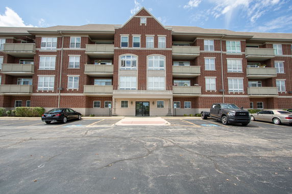 Front view of a multi-story brick building with balconies and parking area.