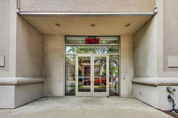 Front view of the entrance to a building with glass doors and an overhead illuminated number sign.
