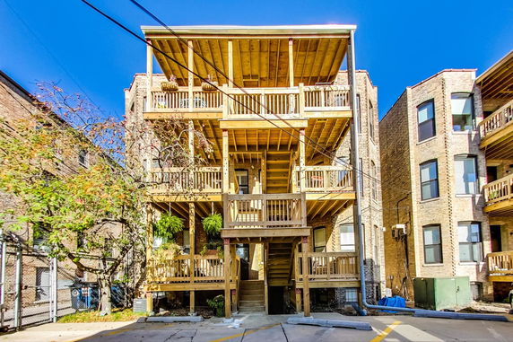 Rear view of a multi-story brick apartment building with wooden balconies and stairs.