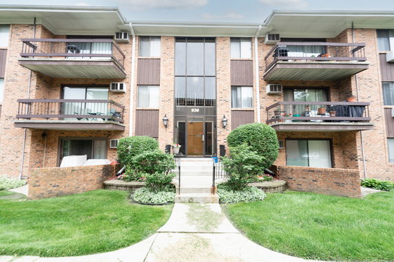 Front view of a multi-story brick apartment building with balconies.