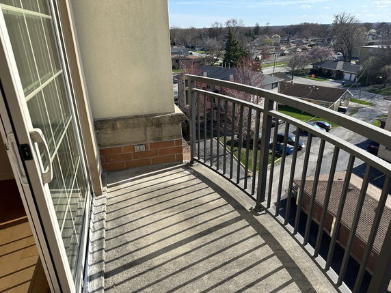View from a balcony overlooking a residential area with houses and trees.