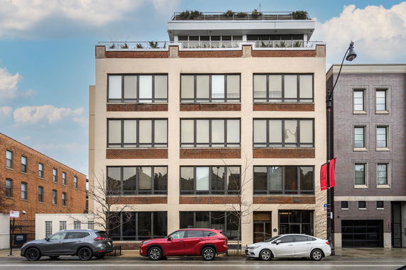 Front view of a multi-story building with large windows and a rooftop garden.