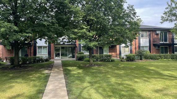 Front view of a two-story residential building with a brick exterior and multiple windows.