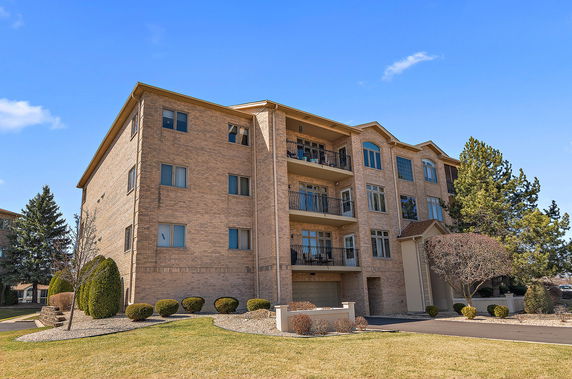 Front view of a multi-story brick apartment building with balconies.