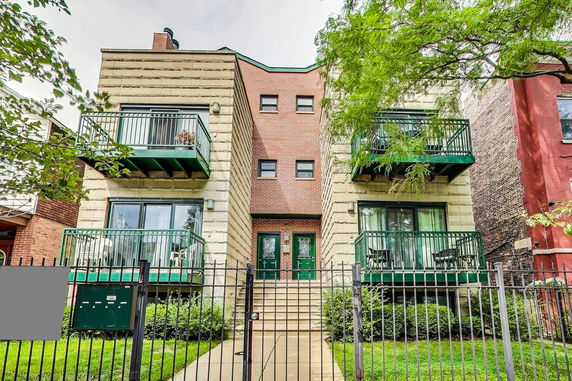 Front view of a multi-story residential building with balconies and a gated entrance.