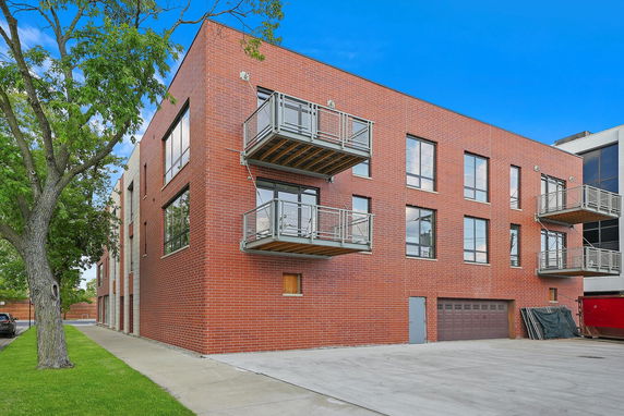 Front view of a multi-story brick building with balconies and large windows.
