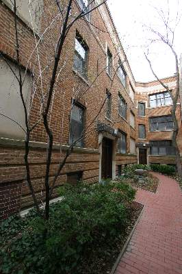 View of a multi-story brick building with multiple windows and a garden path.