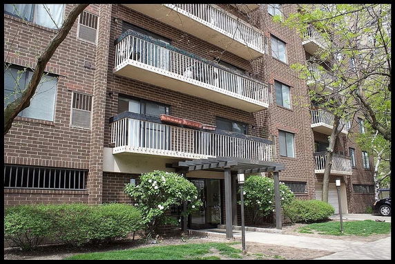 Front view of a multi-story brick apartment building with balconies.