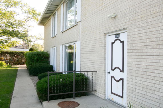Side view of a two-story brick building with windows and a white door.
