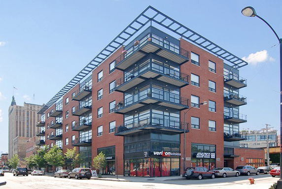 Front view of a multi-story brick building with retail space on the ground floor.