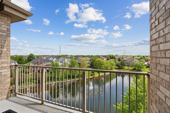 View from a balcony overlooking a suburban neighborhood with houses and a pond.