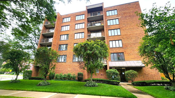 Front view of a multi-story brick apartment building with balconies.