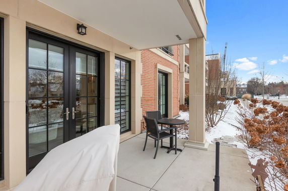 Patio area of a building with seating and a covered area, showing snow-covered surroundings.