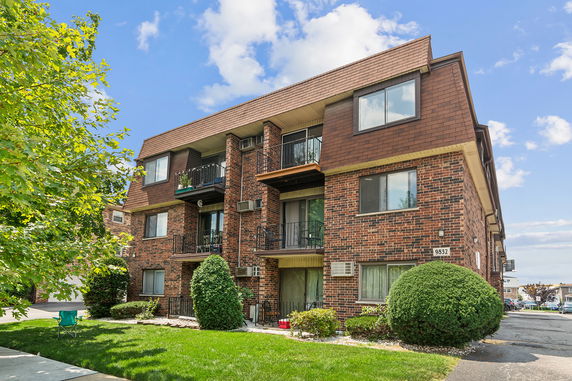 Front view of a multi-story brick apartment building with balconies.