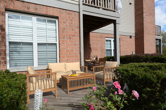 Front view of a house with a brick exterior and a patio featuring outdoor furniture.