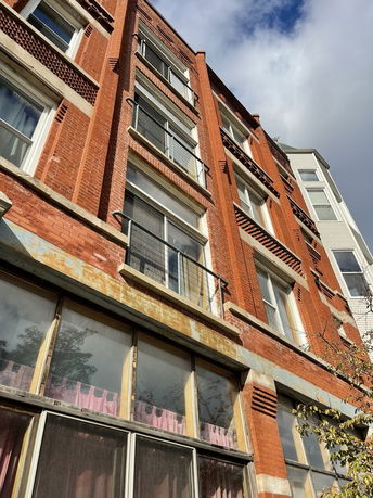 Front view of a multi-story brick building with multiple windows.