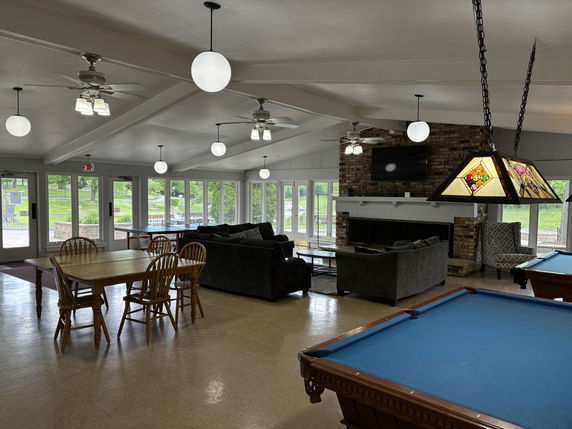 Interior view of a recreation area with pool tables, seating, and a fireplace.
