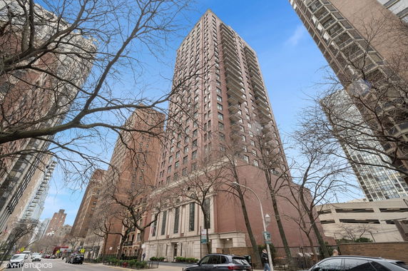 Front view of a tall brick building with numerous windows and balconies.