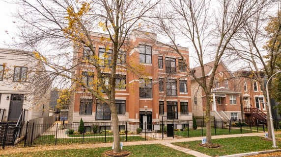 Front view of a three-story brick building with a fenced yard.