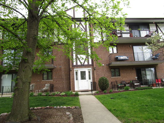 Front view of a multi-story brick apartment building with balconies.