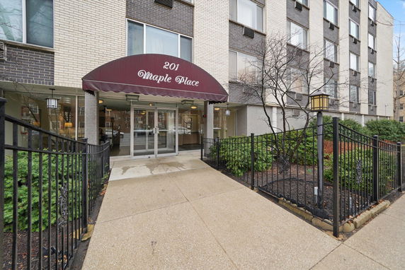 Front view of a multi-story building with an entrance canopy and fence.