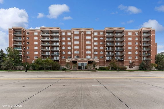 Front view of a multi-story brick residential building with balconies.