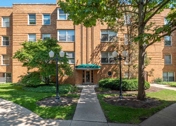 Front view of a brick apartment building with a green awning above the entrance.