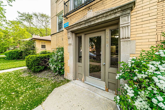 Front view of a brick building entrance with a glass door and decorative stonework.
