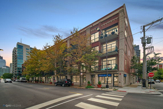 Front view of a multi-story brick building with balconies and street-level shops.