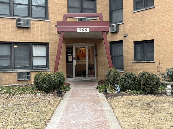 Front view of a brick apartment building entrance with a covered entryway.