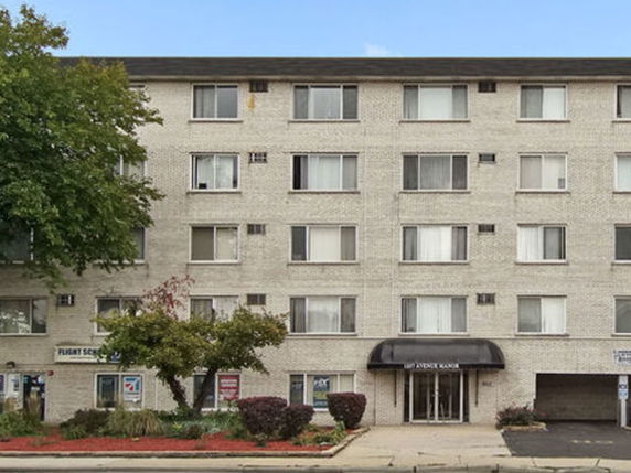 Front view of a multi-story apartment building with a central entrance and multiple windows.