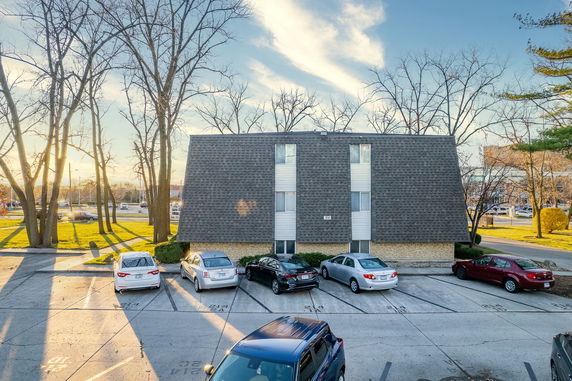 Front view of a multi-story building with sloped roof and vertical windows.