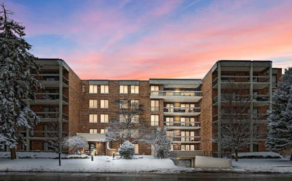 Front view of a multi-story brick apartment building with balconies during winter.
