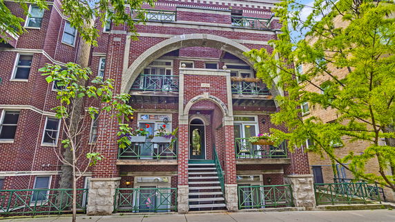 Front view of a multi-story brick building with arched entrances and balconies.