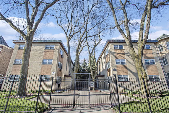 Front view of a multi-story apartment building with a gated entrance.