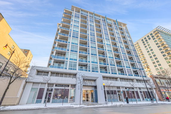 Front view of a multi-story building with glass balconies.
