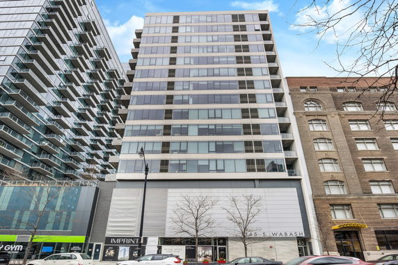Front view of a modern multi-story building with large windows and balconies.
