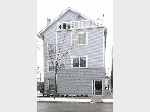 Front view of a three-story house with a balcony on the top floor.