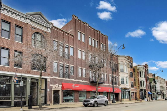 Front view of a multi-story brick building with several businesses at street level.