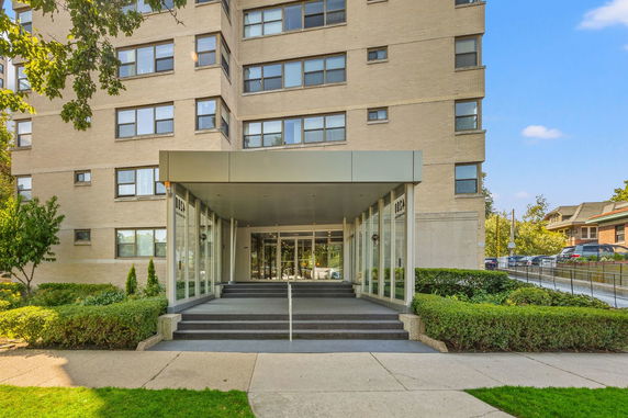 Front view of a multi-story building with a glass entrance and steps.