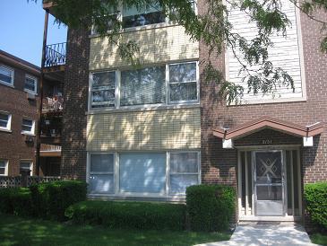 Front view of a multi-story apartment building with brick and light-colored panels.