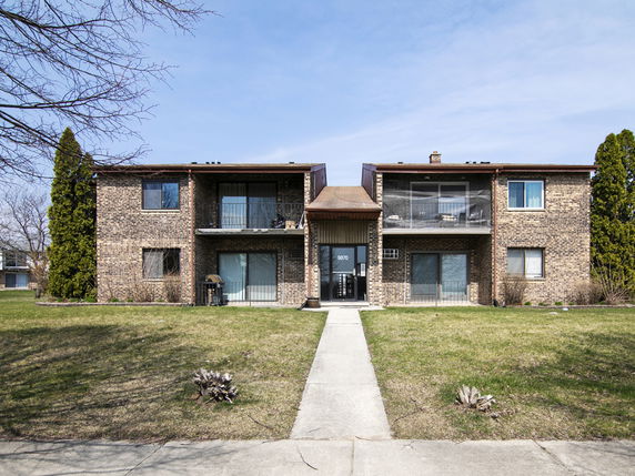 Front view of a two-story brick apartment building with balconies.