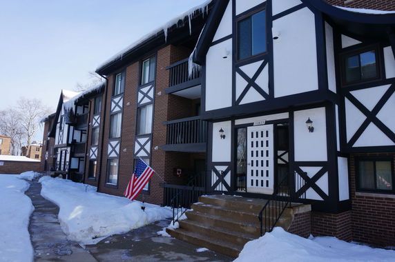 Front view of a multi-story building with Tudor-style architecture and snow-covered ground.