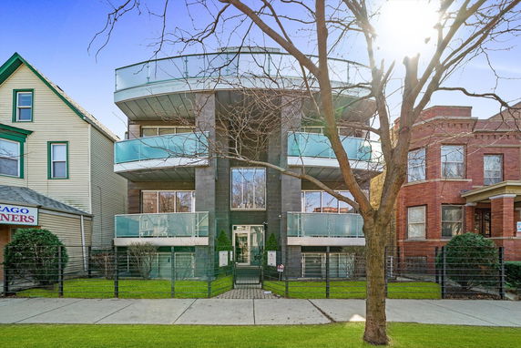 Front view of a modern three-story building with glass balconies.