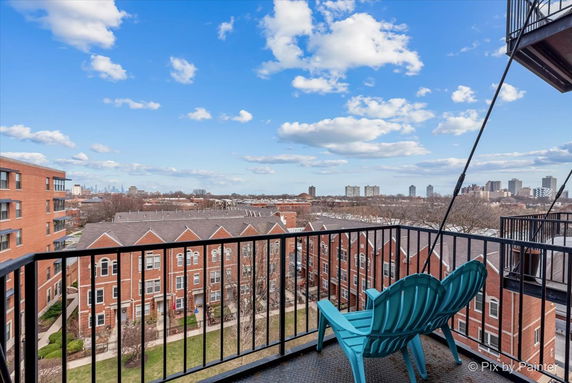 Panoramic view from a balcony overlooking multiple brick buildings with a city skyline in the distance.