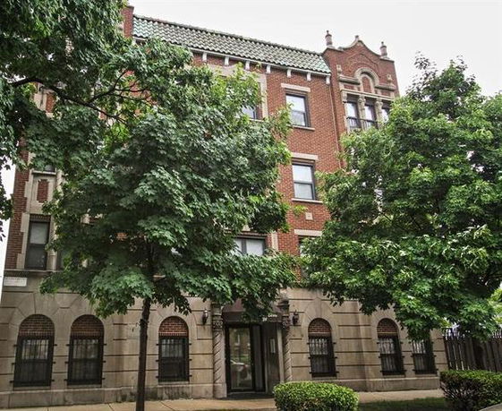 Front view of a multi-story brick building with decorative roof tiles.